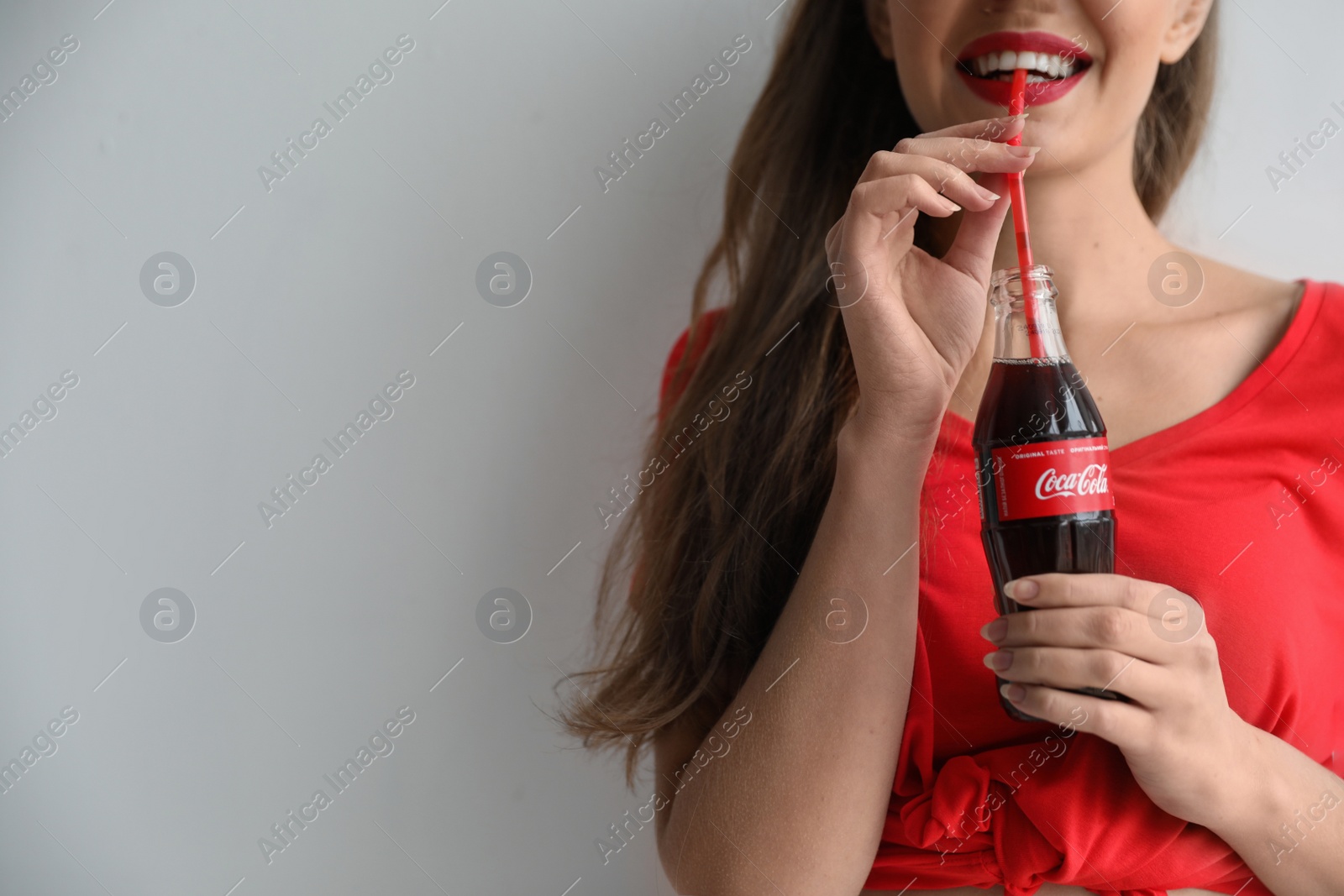 Photo of MYKOLAIV, UKRAINE - NOVEMBER 28, 2018: Young woman with bottle of Coca-Cola on white background, space for text