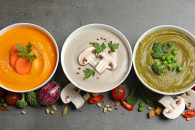 Various cream soups and ingredients on grey background, flat lay. Healthy food