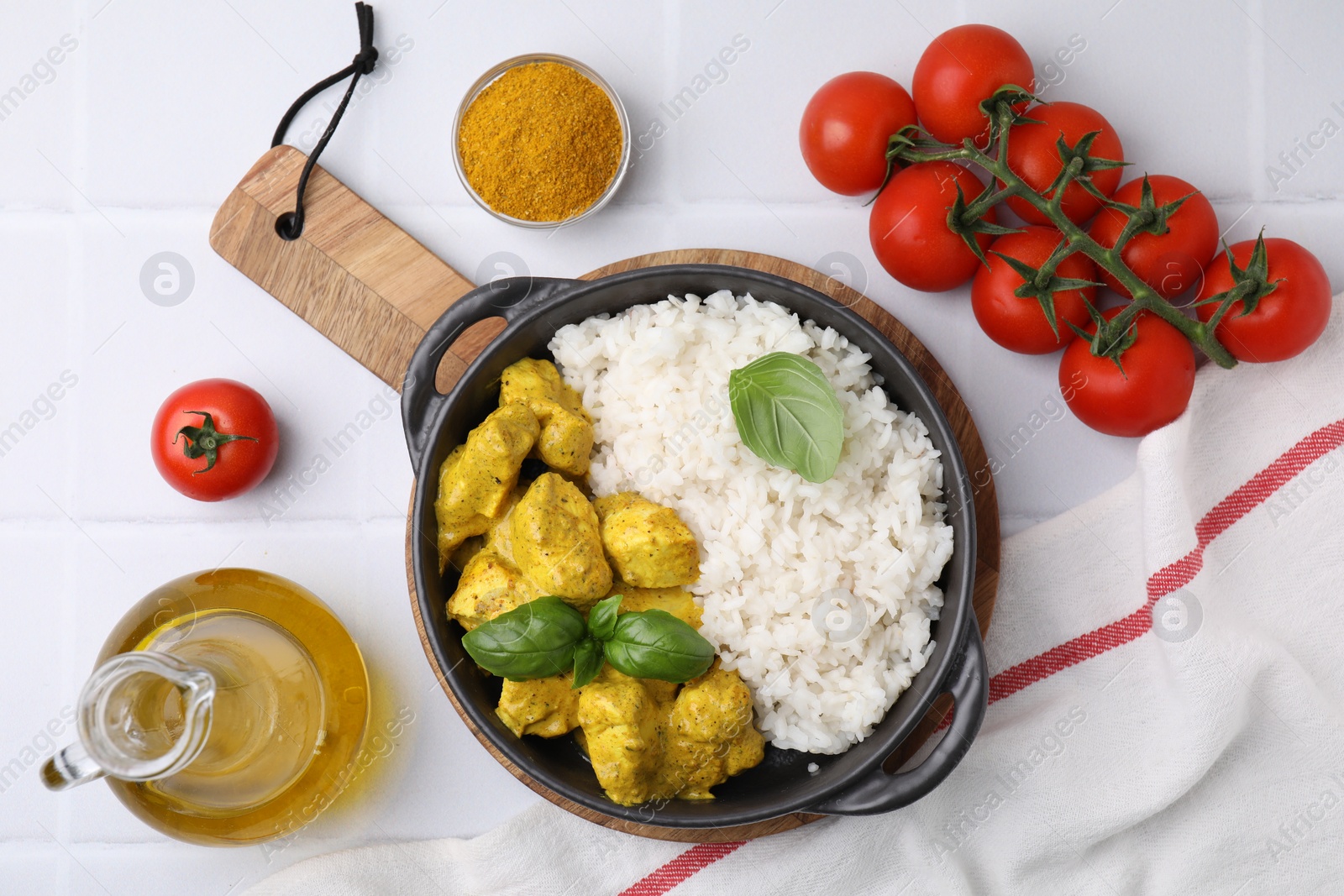 Photo of Delicious rice, chicken with curry sauce and products on white tiled table, flat lay