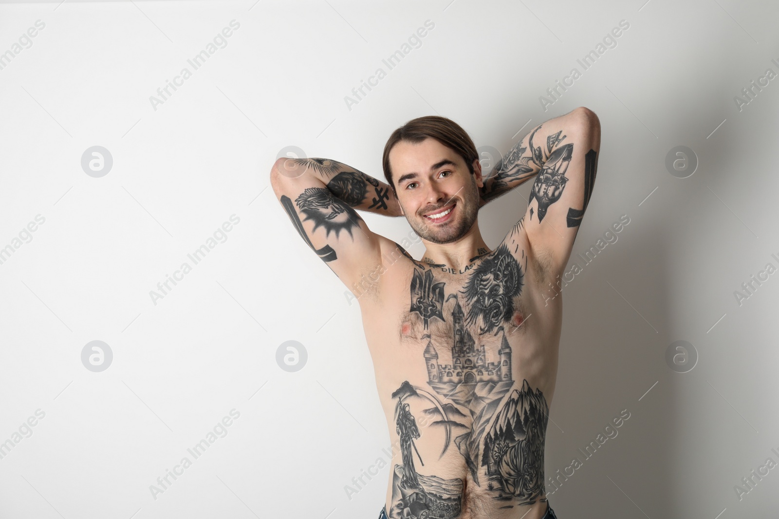 Photo of Young man with tattoos on body against white background