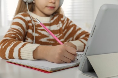 Cute little girl with modern tablet studying online at home, closeup. E-learning