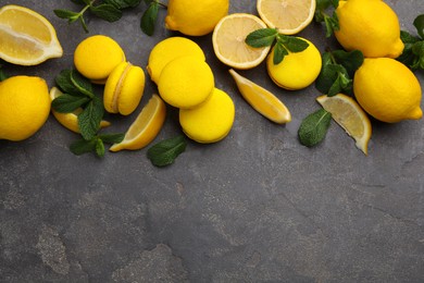 Photo of Delicious yellow macarons, fresh lemons and mint on grey table, flat lay. Space for text