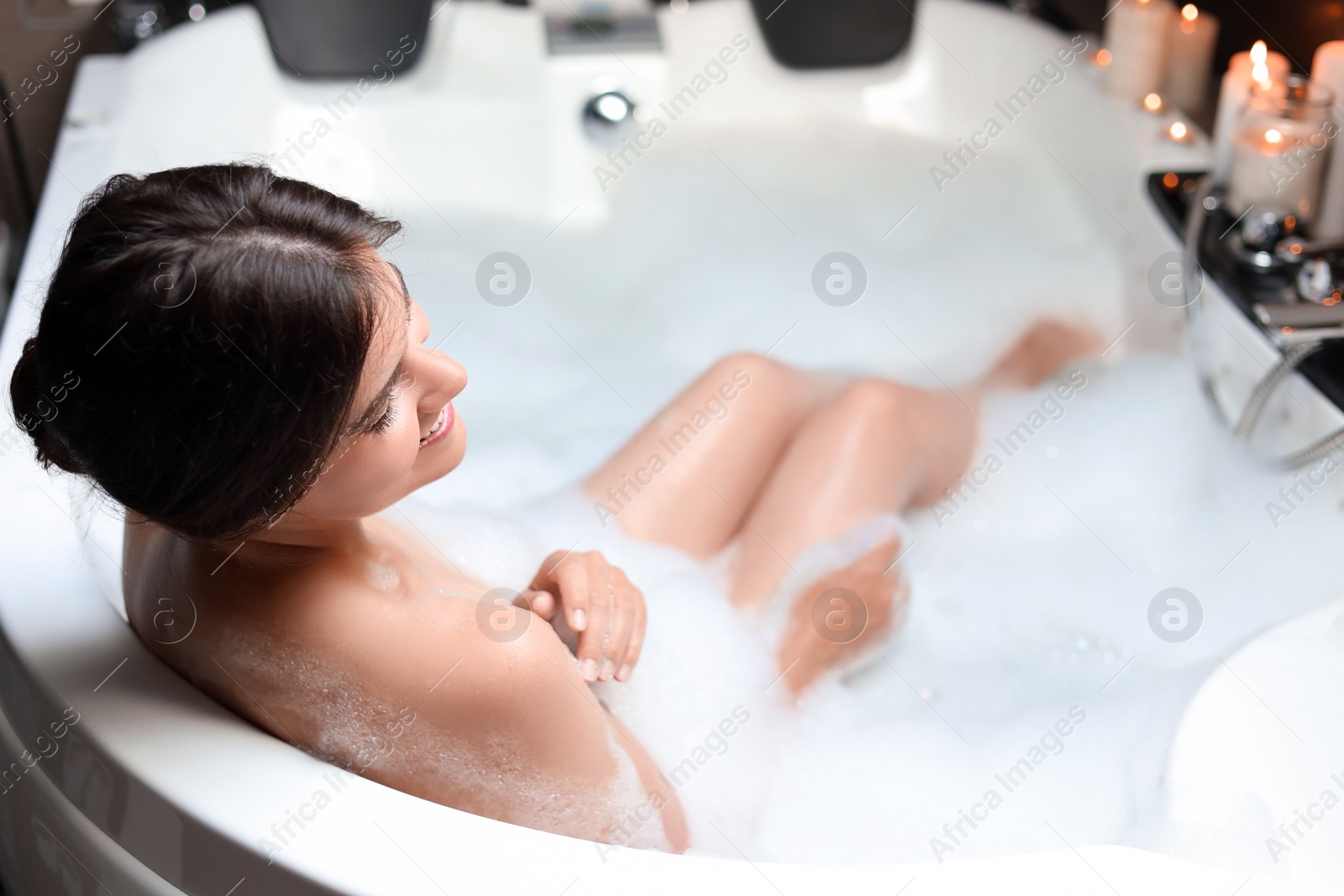 Photo of Happy beautiful woman taking bubble bath. Romantic atmosphere