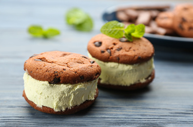 Photo of Sweet delicious ice cream cookie sandwiches on blue wooden table, closeup