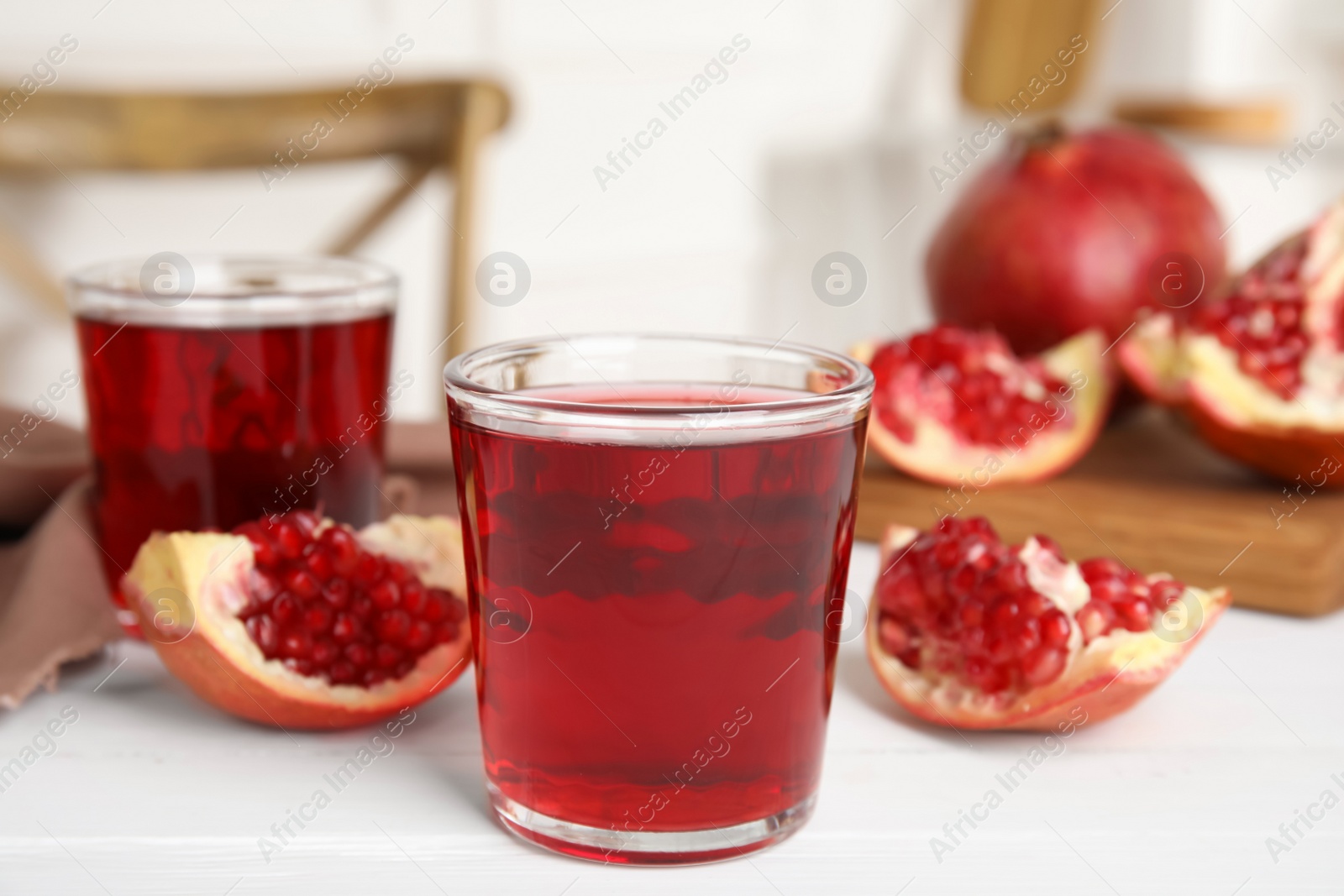 Photo of Pomegranate juice and fresh fruits on white wooden table