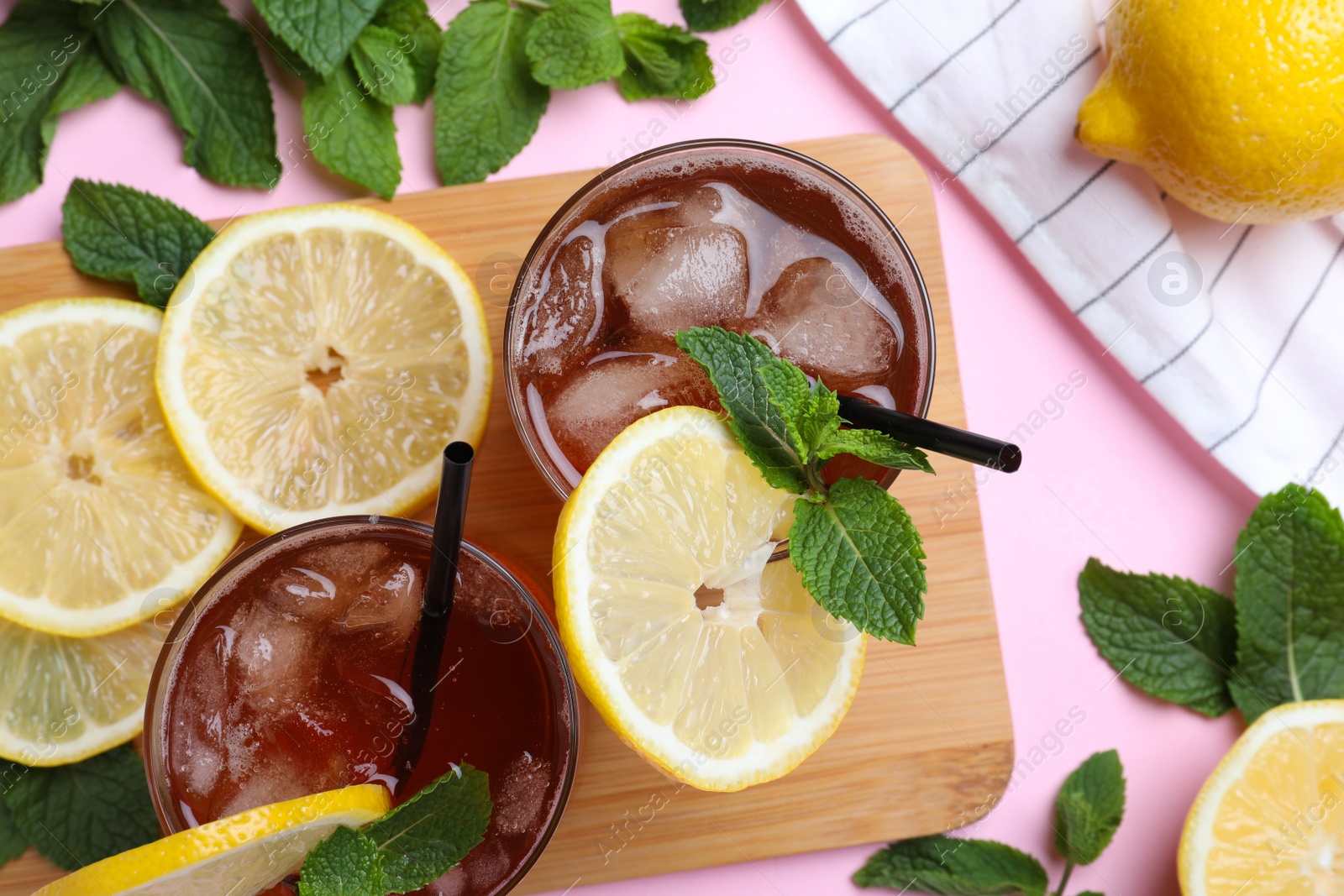 Photo of Delicious iced tea with lemon and mint on pink background, flat lay