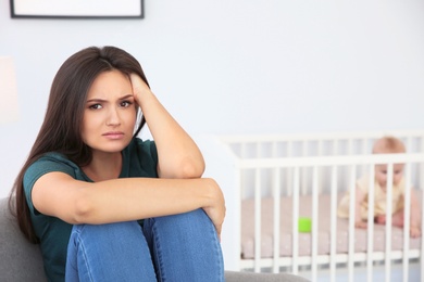 Photo of Young mother suffering from postnatal depression and little baby in room