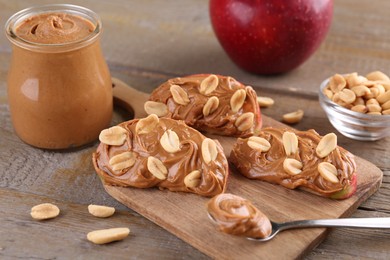 Photo of Slices of fresh apple with peanut butter and nuts on wooden table, closeup