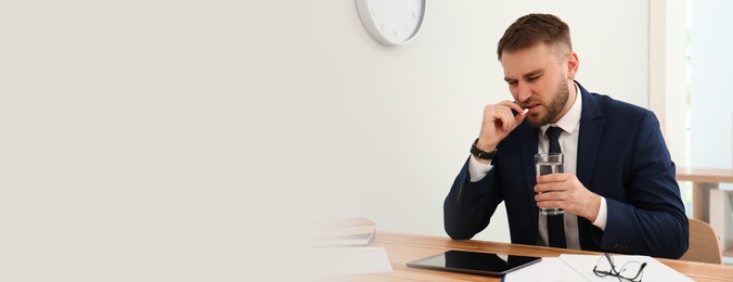 Image of Man taking pill against migraine in office, space for text. Banner design