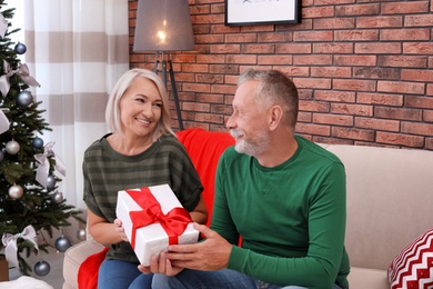 Mature couple with Christmas gift box at home