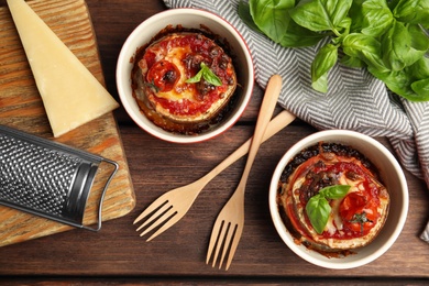 Baked eggplant with tomatoes, cheese and basil served on wooden table, flat lay