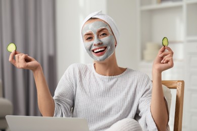 Photo of Young woman with face mask and cucumber slices at home. Spa treatments