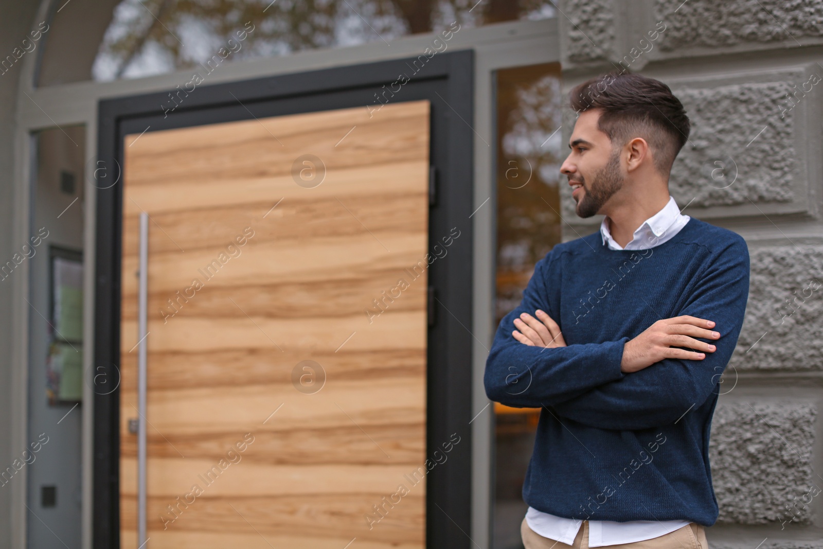 Photo of Young male business owner standing near his cafe. Space for text