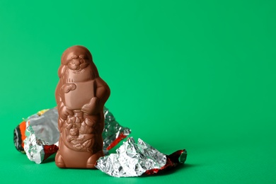 Photo of Unwrapped chocolate Santa Claus on green background. Space for text