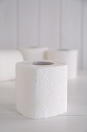 Photo of Soft toilet paper rolls on white wooden table