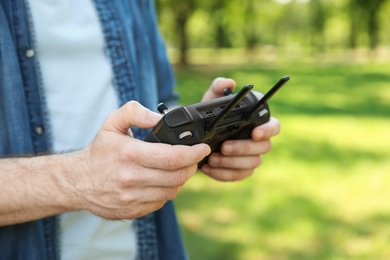 Man holding new modern drone controller outdoors, closeup of hands