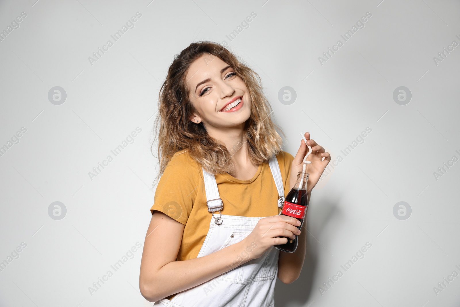 Photo of MYKOLAIV, UKRAINE - NOVEMBER 28, 2018: Young woman with bottle of Coca-Cola on white background