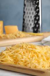 Delicious grated cheese on white wooden table