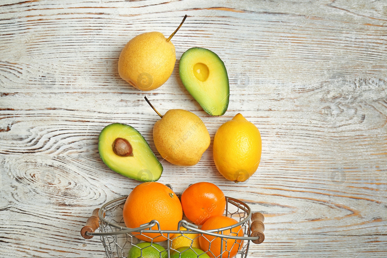 Photo of Metal basket and fresh tropical fruits on wooden background