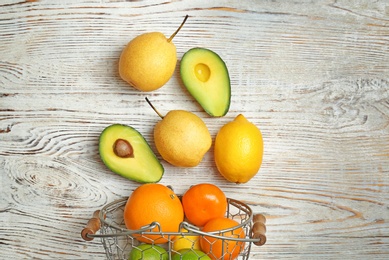 Metal basket and fresh tropical fruits on wooden background