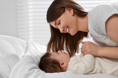 Photo of Happy mother with her little baby on bed at home