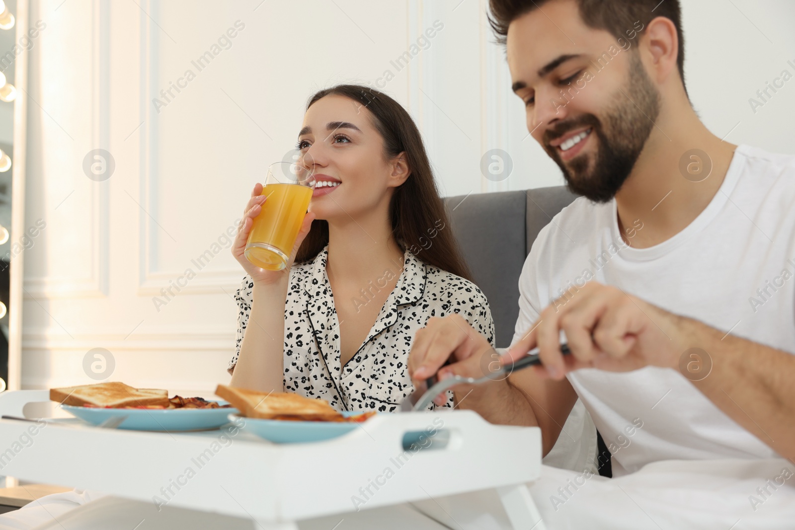 Photo of Happy couple having breakfast on bed at home