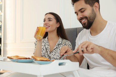 Happy couple having breakfast on bed at home