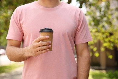 Photo of Man with takeaway coffee cup outdoors, closeup