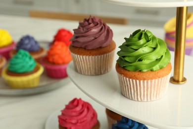 Photo of Delicious cupcakes with colorful cream on stand, closeup