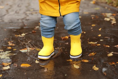 Photo of Little girl walking in puddle outdoors, closeup