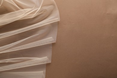 Beautiful tulle fabric on brown background, top view. Space for text
