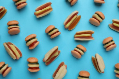 Photo of Tasty jelly candies in shape of burger and hot dog on light blue background, flat lay