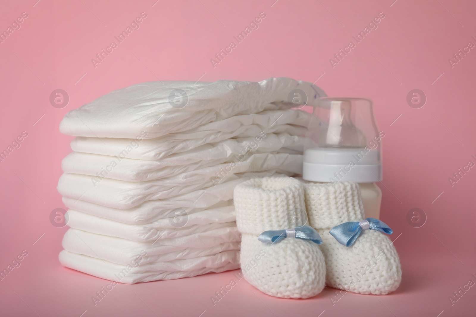 Photo of Diapers and baby accessories on pink background