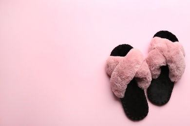 Photo of Pair of soft slippers on light pink background, flat lay. Space for text