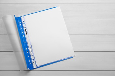 Photo of File folder with punched pockets and paper sheets on white wooden table, top view. Space for text