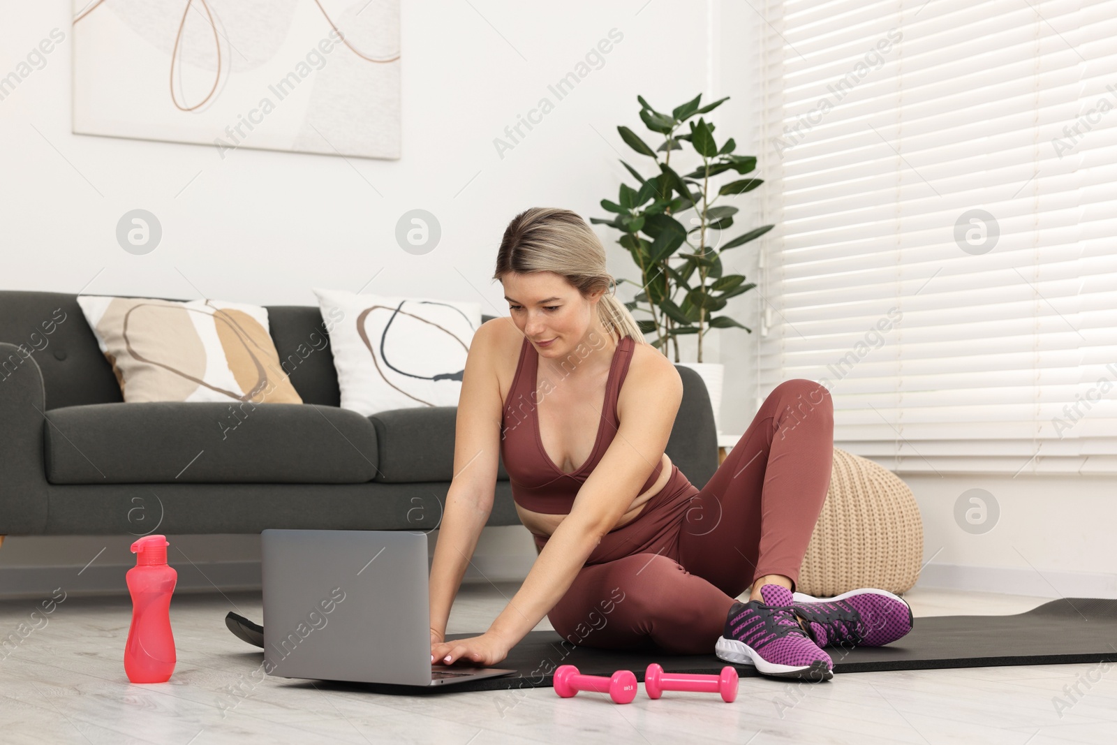 Photo of Online fitness trainer. Woman watching tutorial on laptop at home