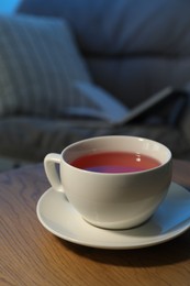 Photo of Cup of hot tea on wooden table at night