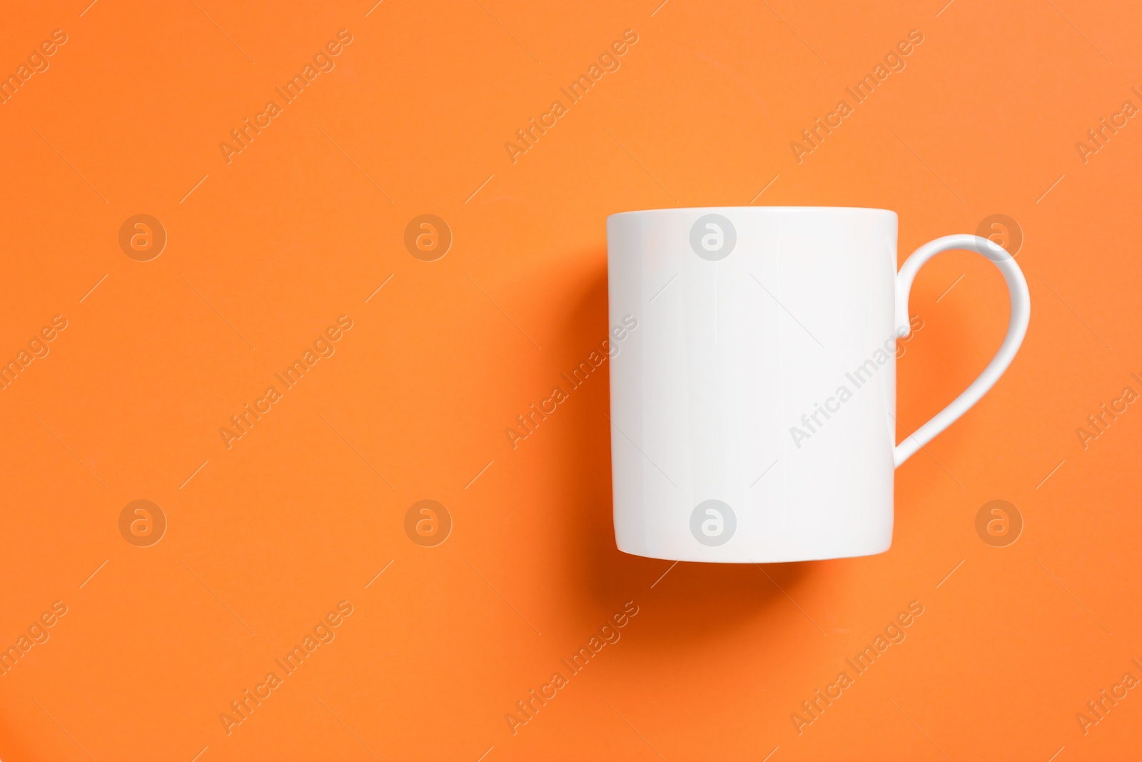 One white ceramic mug on orange background, top view. Space for text Photo of One white ceramic mug on orange background, top view. Space for text