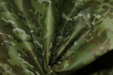 Photo of Texture of crumpled camouflage fabric as background, top view