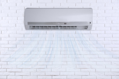 Image of Modern air conditioner on white brick wall indoors