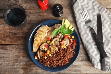 Plate with quinoa and garnish on table, top view