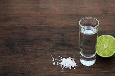 Photo of Mexican tequila shots with lime and salt on wooden table. Space for text