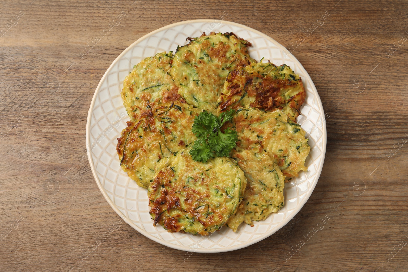 Photo of Delicious zucchini fritters served on wooden table, top view