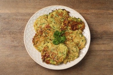 Delicious zucchini fritters served on wooden table, top view