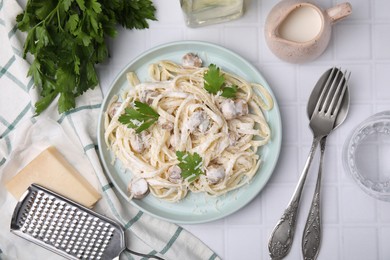 Delicious pasta with mushrooms served on white tiled table, flat lay