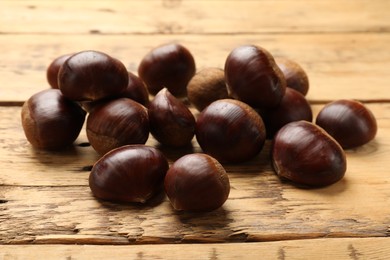 Sweet fresh edible chestnuts on wooden table, closeup