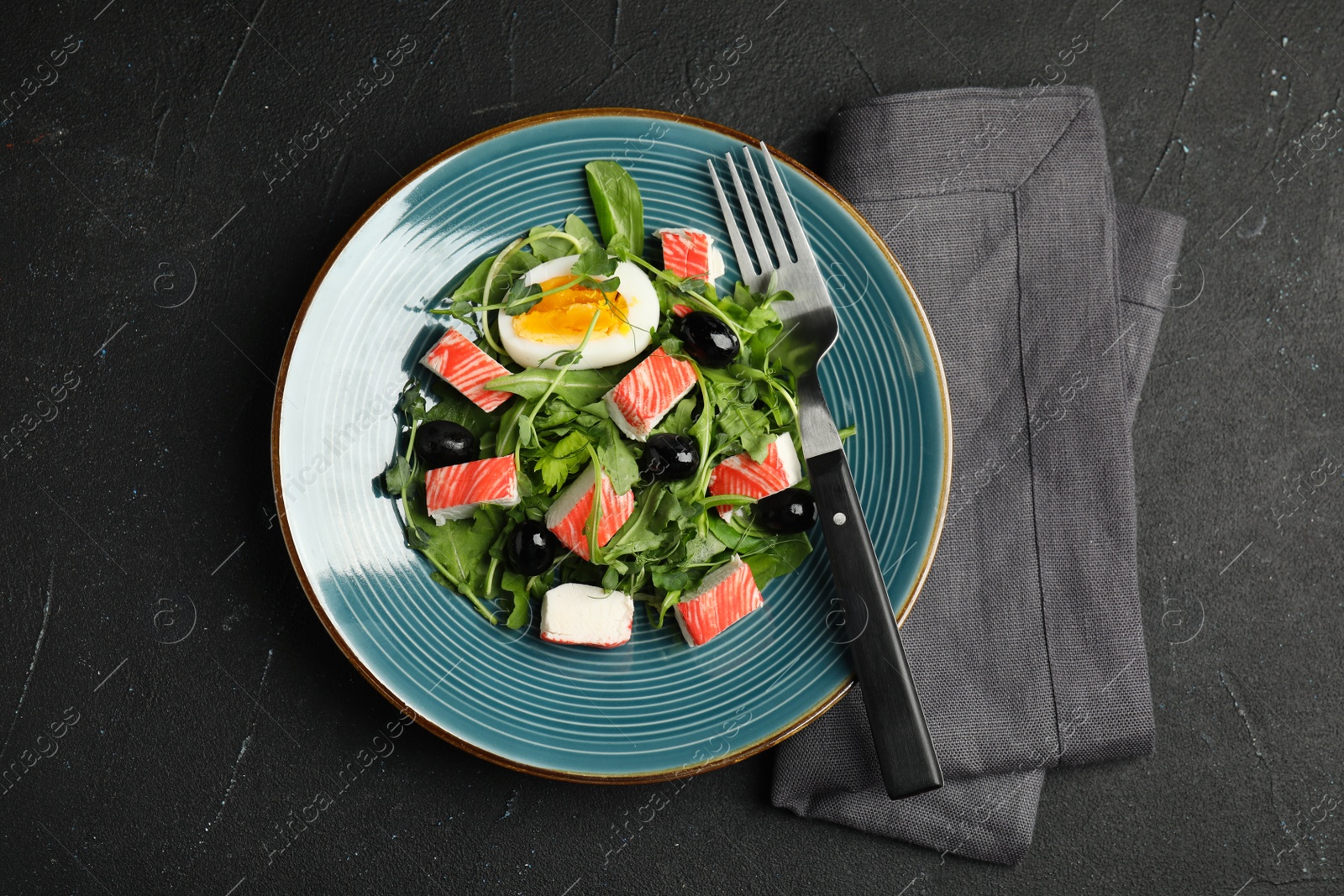 Photo of Delicious crab stick salad served on black table, flat lay