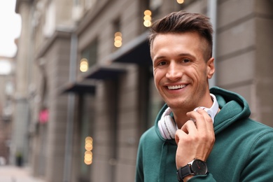 Portrait of handsome young man with headphones outdoors. Space for text