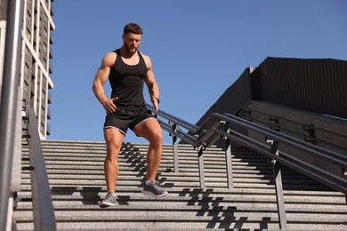 Man running down stairs outdoors on sunny day, low angle view