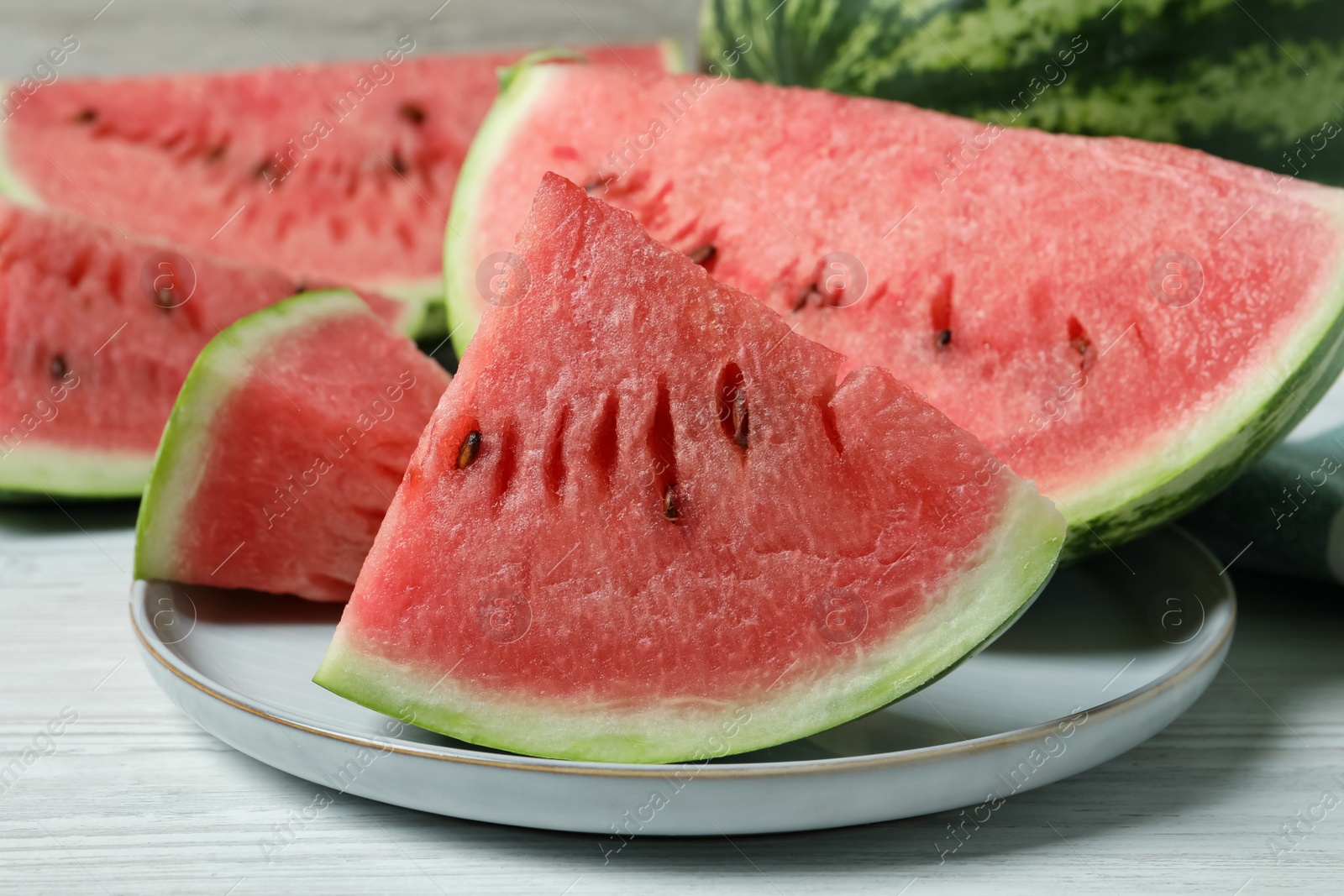 Photo of Slices of tasty ripe watermelon on white wooden table, closeup